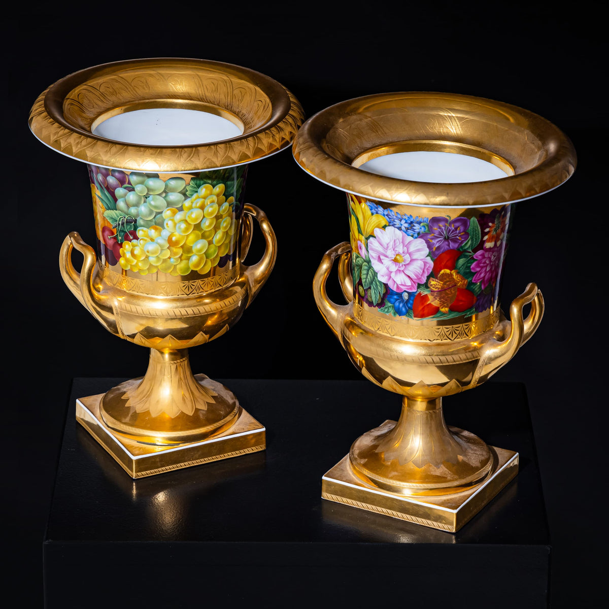 Two ornate vases with gold detailing and colorful floral designs on a black background