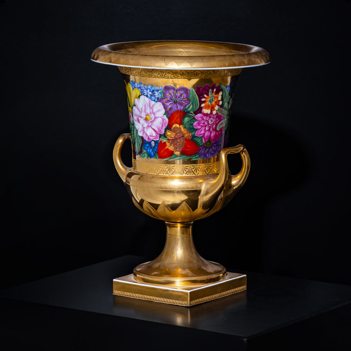 Decorative urn with floral design and gold accents on a black background