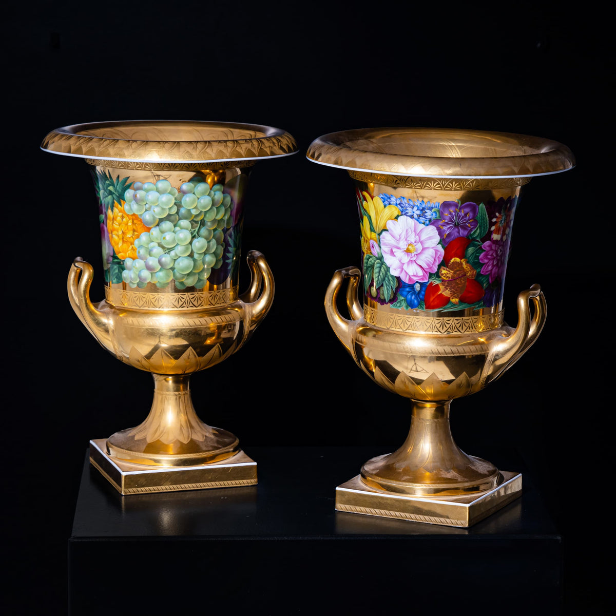 Two ornate vases with floral and fruit designs on a black background
