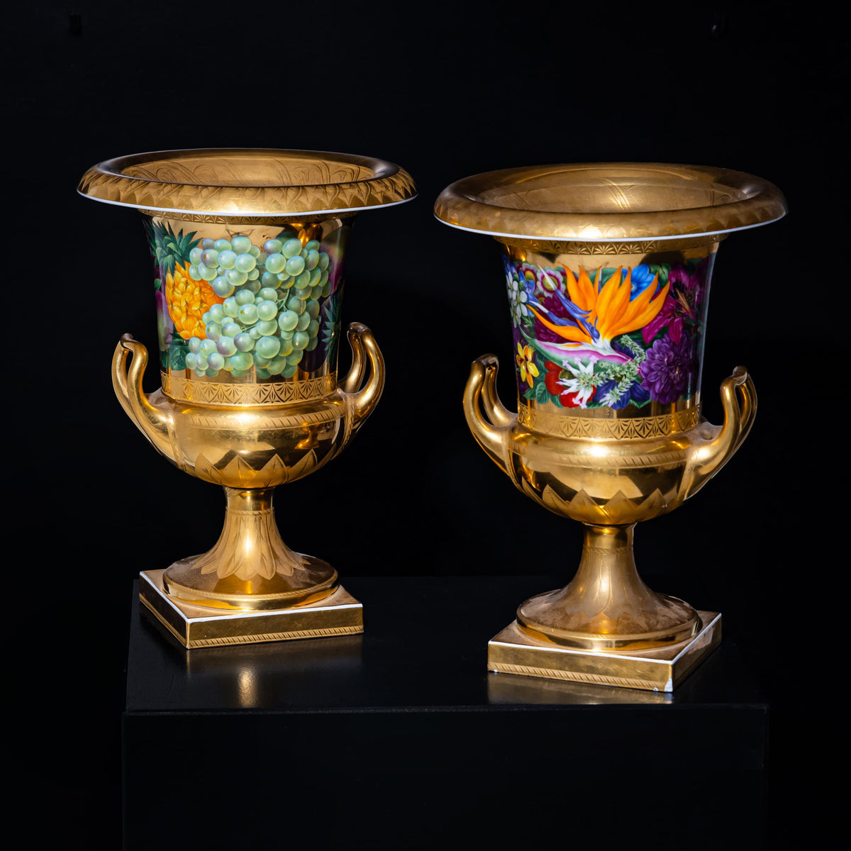 Two ornate gold urns with colorful designs on a black background