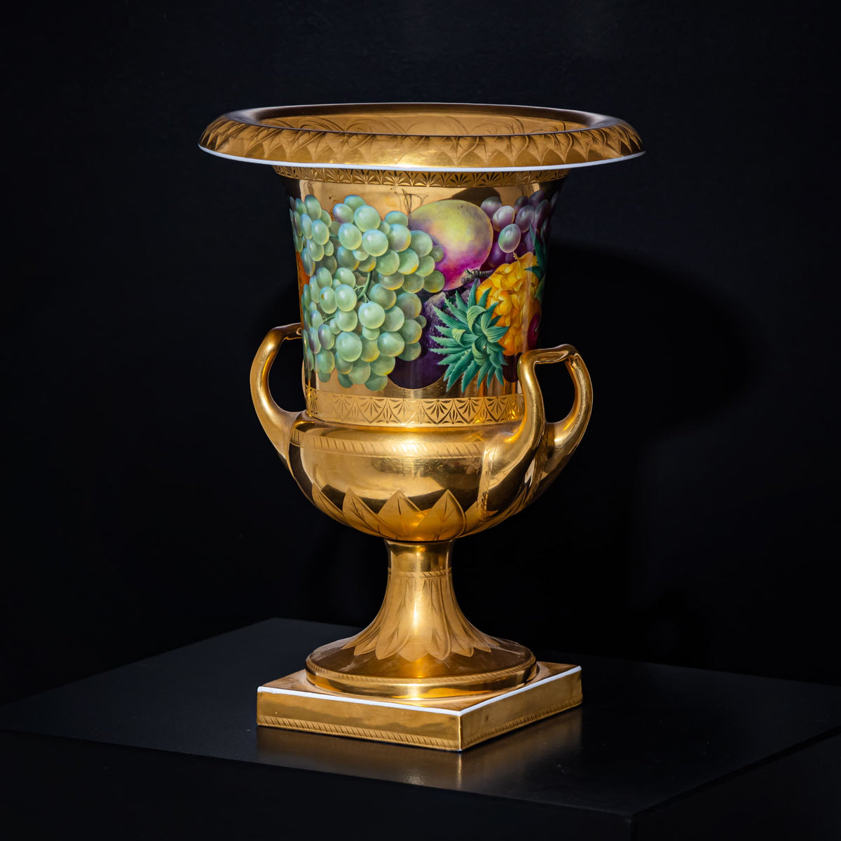 Decorative urn with gold detailing and fruit design on a black background